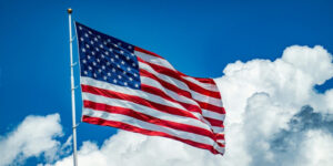 American flag waving against a bright blue sky, symbolizing the freedom and clarity that come from well-being.