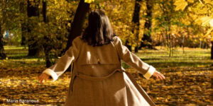 Woman standing in an autumn park reflecting on well-being and reconnecting with themselves during the back‑to‑school season.